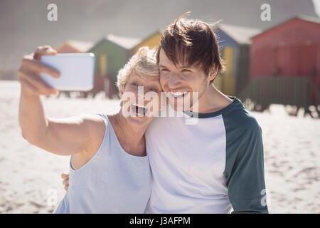 Fröhliche Frau mit Sohn nehmen Selfie am Strand während der sonnigen Tag Stockfoto