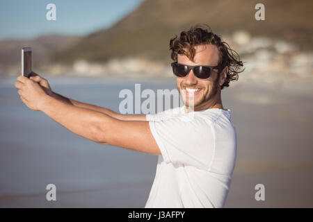 Porträt von lächelnden Mann nehmen Selfie am Strand im sonnigen Tag Stockfoto