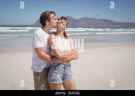 Junger Mann, die Frau am Strand im sonnigen Tag küssen Stockfoto