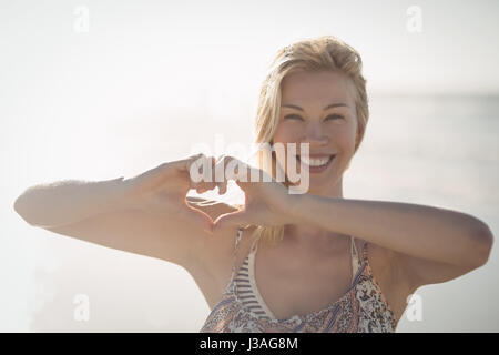 Porträt der Frau Herzform mit Händen am Strand im sonnigen Tag machen Stockfoto