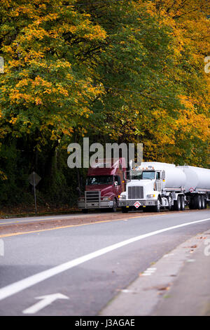 Moderne weiße Tag cab Semi Truck und Dunkelrot Long Haul Big Rig mit verchromten Kühlergrill und zwei Tanks Anhänger von geraden multy-line Road Stockfoto