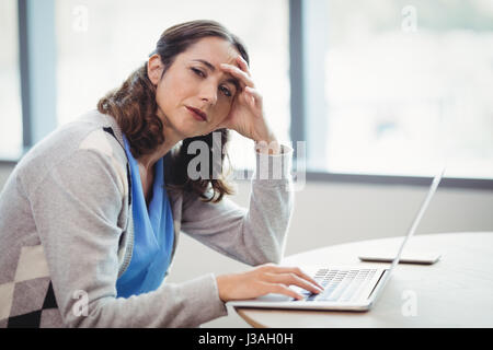 Porträt müde Executive mit Laptop am Schreibtisch im Büro Stockfoto