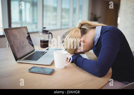 Müde Geschäftsfrau stützte sich auf den Schreibtisch im Büro Stockfoto