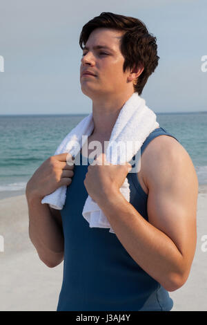 Nachdenklicher Mann mit Handtuch um den Hals stehen am Strand Stockfoto