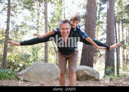 Porträt der fröhlichen Vater Sohn beim Wandern im Wald Huckepack Stockfoto