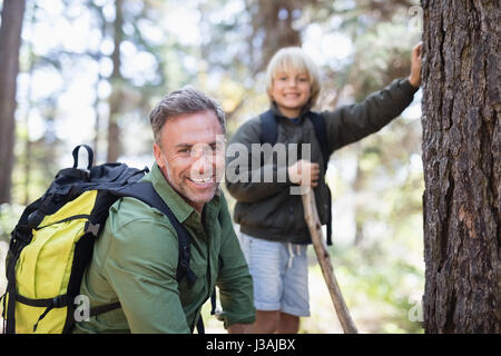 Porträt des Lächelns, Vater und Sohn tragen Rucksäcke beim Wandern im Wald Stockfoto