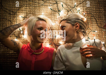 Zwei Freunde auf dem Boden liegend mit Lichterketten Stockfoto