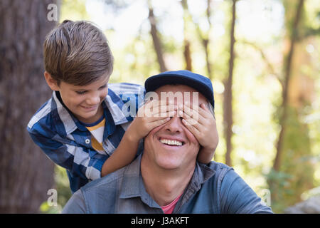 Verspielte Junge Väter Augen im Wald bedecken Stockfoto