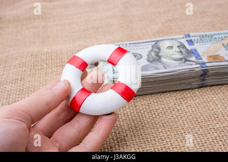 Rettungsring in der Hand über die Banknote Bündel von US-dollar Stockfoto