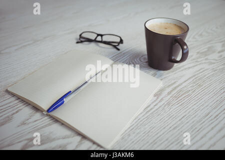 Erhöhte Ansicht von Stift und Buch mit Kaffeetasse am Tisch Stockfoto