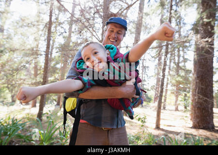 Spielerische Reife Vater mit Sohn gegen Bäume im Wald Stockfoto