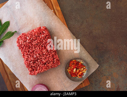 Frisches Hackfleisch und Gewürze auf dem Metzger Papier, bereit für das Kochen. Ansicht von oben, Leerzeichen Stockfoto