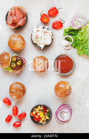 Vorbereitung hausgemachte Burger, verschiedenen Füllungen auf rustikale Oberfläche. Ansicht von oben, Leerzeichen Stockfoto