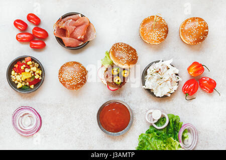 Vorbereitung hausgemachte Burger, verschiedenen Füllungen auf rustikale Oberfläche. Ansicht von oben, Leerzeichen Stockfoto