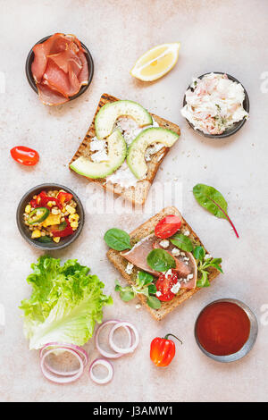 Offenen Vollkorn Sandwiches und verschiedenen Zutaten auf rustikale Oberfläche. Ansicht von oben, Leerzeichen Stockfoto