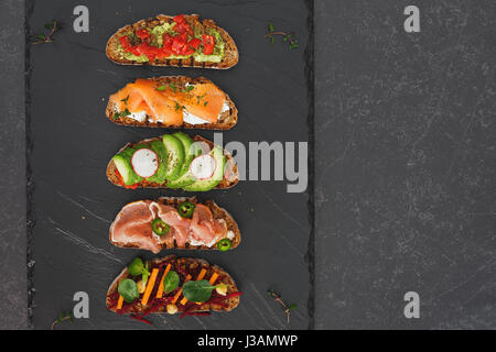 Offenen Roggenbrot Brötchen belegt mit Lachs, Avocado, rote Beete, Frischkäse, Schinken und anderen Zutaten. Ansicht von oben, Leerzeichen Stockfoto