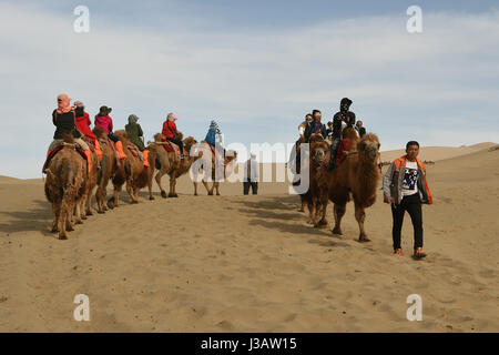 Der Provinz Gansu Dunhuang, China. 3. Mai 2017. Touristen fahren Kamele an berühmte Sand Berg oder die singenden Sanddünen in Dunhuang, Nordwesten Chinas Provinz Gansu, 3. Mai 2017. Berühmte Sand Landschaft Bergzone in Dunhuang hat vor kurzem zahlreiche Touristen angezogen. Bildnachweis: Fan Peishen/Xinhua/Alamy Live-Nachrichten Stockfoto