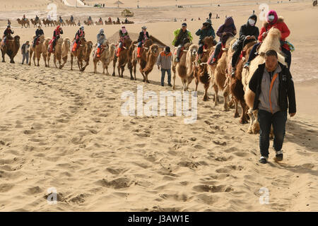 Der Provinz Gansu Dunhuang, China. 3. Mai 2017. Touristen fahren Kamele an berühmte Sand Berg oder die singenden Sanddünen in Dunhuang, Nordwesten Chinas Provinz Gansu, 3. Mai 2017. Berühmte Sand Landschaft Bergzone in Dunhuang hat vor kurzem zahlreiche Touristen angezogen. Bildnachweis: Fan Peishen/Xinhua/Alamy Live-Nachrichten Stockfoto