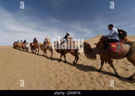 Der Provinz Gansu Dunhuang, China. 3. Mai 2017. Touristen fahren Kamele an berühmte Sand Berg oder die singenden Sanddünen in Dunhuang, Nordwesten Chinas Provinz Gansu, 3. Mai 2017. Berühmte Sand Landschaft Bergzone in Dunhuang hat vor kurzem zahlreiche Touristen angezogen. Bildnachweis: Fan Peishen/Xinhua/Alamy Live-Nachrichten Stockfoto