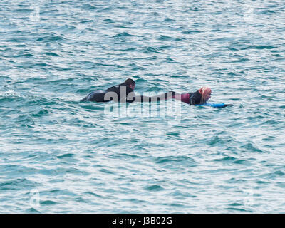 Newquay, Großbritannien. 4. Mai 2017. Rettung auf See von Rettungsschwimmern bewacht. 4. Mai 2017. Ein Mann und eine Frau auf Surfbretter sind durch die Felsen auf dem South by RNLI Rettungsschwimmer auf einen Jetski am Fistral Strand fistral Newquay, Cornwall, UK aus der Brandung gerettet.  Robert Taylor/Alamy Live-Nachrichten Stockfoto