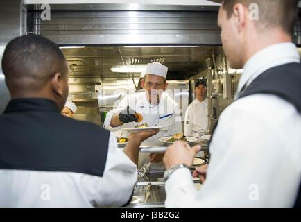 Bereiten Sie Starkoch Udo Müller, Zentrum, neben der US Navy Matrosen Mittagessen an Bord der amphibischen Landung Dock USS New York während der 27. jährliche Fleet Week 3. Mai 2017 in Port Everglades, Florida. Stockfoto
