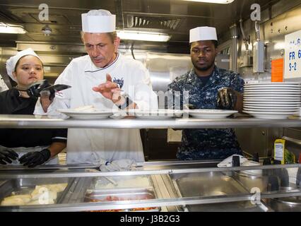 Bereiten Sie Starkoch Udo Müller, Zentrum, neben der US Navy Matrosen Mittagessen an Bord der amphibischen Landung Dock USS New York während der 27. jährliche Fleet Week 3. Mai 2017 in Port Everglades, Florida. Stockfoto