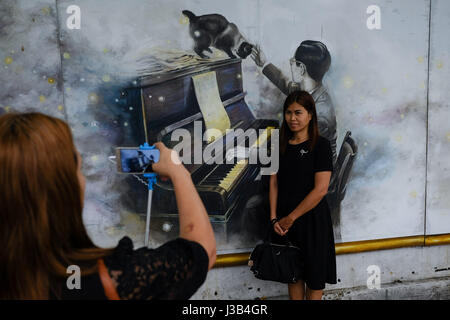 Bangkok, Thailand. 5. Mai 2017. Ein Trauernder posiert für Fotos mit einem Fresko von der späten König Bhumibol Adulyadej in der Nähe des Sanam Luang in Bangkok, Thailand, 5. Mai 2017. Thai trauernden weiter strömen in Bangkoks Sanam Luang Platz gegenüber dem späten König Bhumibol Adulyadej am Freitag, trotz der offiziellen Absage des 5. Mai als den Tag der Krönung zu bezahlen. König Bhumibol, die früher der weltweit am längsten regierende Monarch, verstarb am 13. Oktober 2016 in Bangkoks Siriraj Krankenhaus. Bildnachweis: Xinhua/Alamy Live-Nachrichten Stockfoto