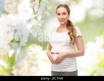 glücklich schwanger Frau zeigt Herz Geste Stockfoto