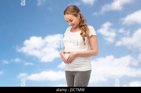 glücklich schwanger Frau zeigt Herz Geste Stockfoto