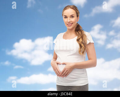 glücklich schwanger Frau zeigt Herz Geste Stockfoto