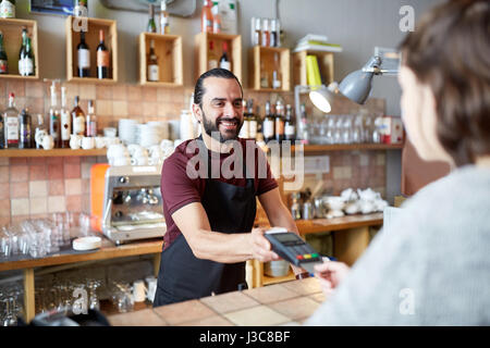Mann oder Kellner mit Kartenleser und Kunden in Bar Stockfoto