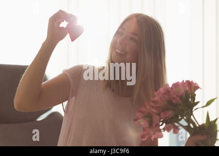 Schöne Frau mit roten Herzen und Haufen von Blume zu Hause Stockfoto