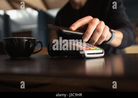 Mann, die Zahlung der Rechnung durch Smartphone mit NFC-Technologie in CafÃƒÂ © Stockfoto