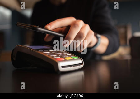 Mann, die Zahlung der Rechnung durch Smartphone mit NFC-Technologie in CafÃƒÂ © Stockfoto