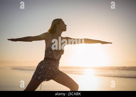 Junge Frau praktizieren Yoga am Strand während der Dämmerung Stockfoto