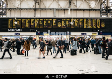 Pendler gehen vorbei an der Abfahrtstafel im Zentrum von London Waterloo Station. Stockfoto