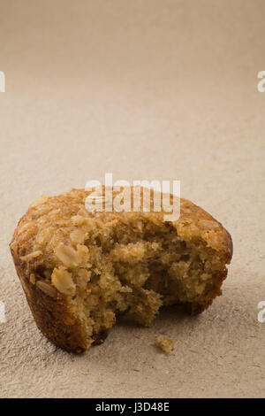 Nahaufnahme von einem teilweise verbraucht alle Kleie-Muffins auf einem strukturierten Beige Papierhintergrund Stockfoto