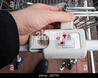 Hand des Mannes Entriegelung Lockeck Trolley im Supermarkt für Lebensmittel einkaufen Stockfoto