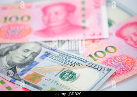 Chinesische Renminbi 100 und 100 US-Dollar Rechnungen gestapelt auf einem weißen Hintergrund. Stockfoto