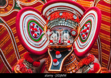 Theyyam Performer in voller bunter Kostüm, Gesichtsmaske und Make-up während einer late-Night-Aufführung von Theyyam in einem Dorf in der Nähe von Kannur, Kerala, Indien. Stockfoto