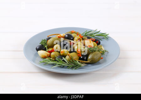 Teller mit grünen und schwarzen Oliven mit Knoblauch, Kapern und Kapern Beeren Stockfoto