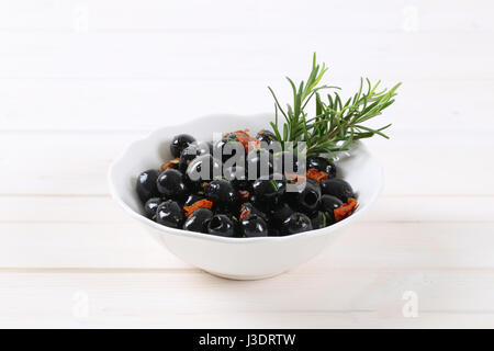 Schale mit schwarzen Oliven mit getrockneten Tomaten auf weißem Hintergrund Stockfoto