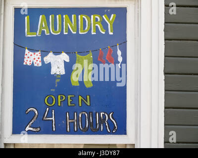 Handgemaltes Schild Werbung Haushaltswäsche Geschäft auf Fenster schließen auf blauem Hintergrund. Stockfoto