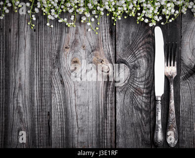 Besteck auf den grauen aus Holz Oberfläche, leeren Raum in der Mitte, Dekoration mit Blumen von Maiglöckchen Stockfoto