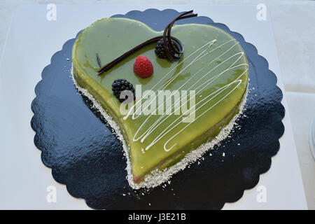 Herzförmige Torte garniert mit Pistaziencreme Stockfoto