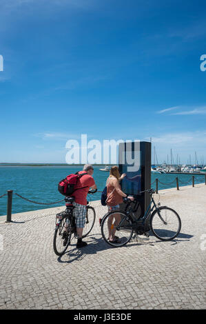 paar Touristen auf Fahrrädern mit einem interaktiven Touristenkarte in Olhao, Algarve, Portugal Stockfoto