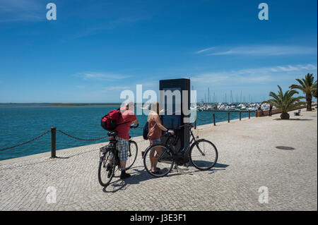 paar Touristen auf Fahrrädern mit einem interaktiven Touristenkarte in Olhao, Algarve, Portugal Stockfoto