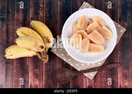 Thai beliebtes Dessert, fertig gekochte Banane in Sirup serviert und Löcher Banane serviert auf Holz. Stockfoto
