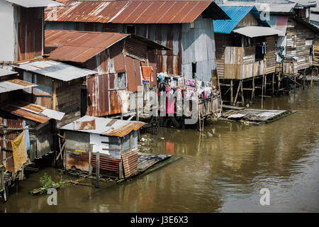 Grundlegende einfache Behausungen in Form von hölzernen Hütten oder Häusern, die den riverine Kalimantan am Flussufer in indonesischen Borneo Einwohner hat. Stockfoto