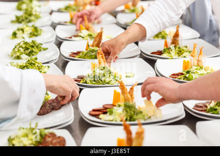 Köche bereiten leckere Vorspeise Speisen an Bord Restaurant Küche Stockfoto